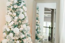 a small Christmas tree decorated with oversized matte white ornaments, semi sheer ribbons, pompoms and lights is fantastic