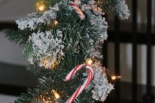 a snowy evergreen garland with lights and candy canes is a very cool idea for styling railing or a mantel is a fun and catchy idea