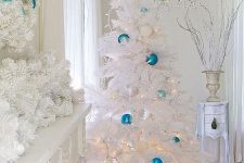 a stunning white and blue coastal Christmas space with a lush garland, a matching wreath and a Christmas tree dotted with the same ornaments and lights