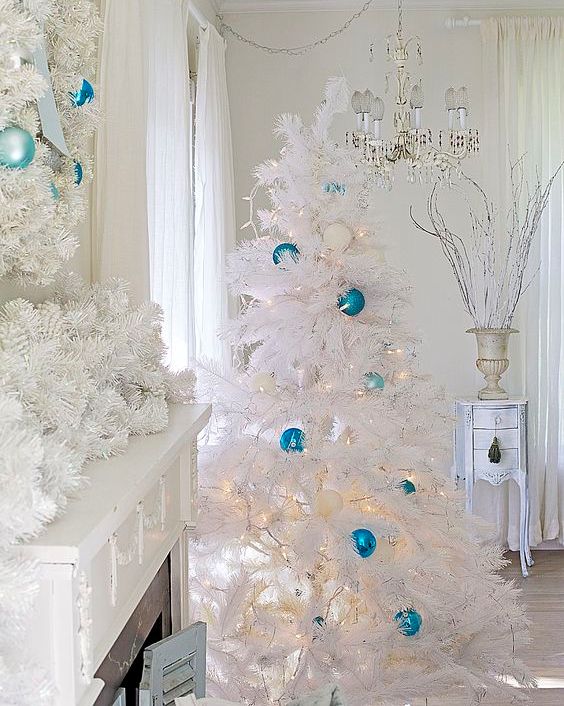a stunning white and blue coastal Christmas space with a lush garland, a matching wreath and a Christmas tree dotted with the same ornaments and lights