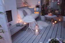 a super cozy winter terrace with a built-in fireplace, a bench, lights, candles, lanterns, potted flowers