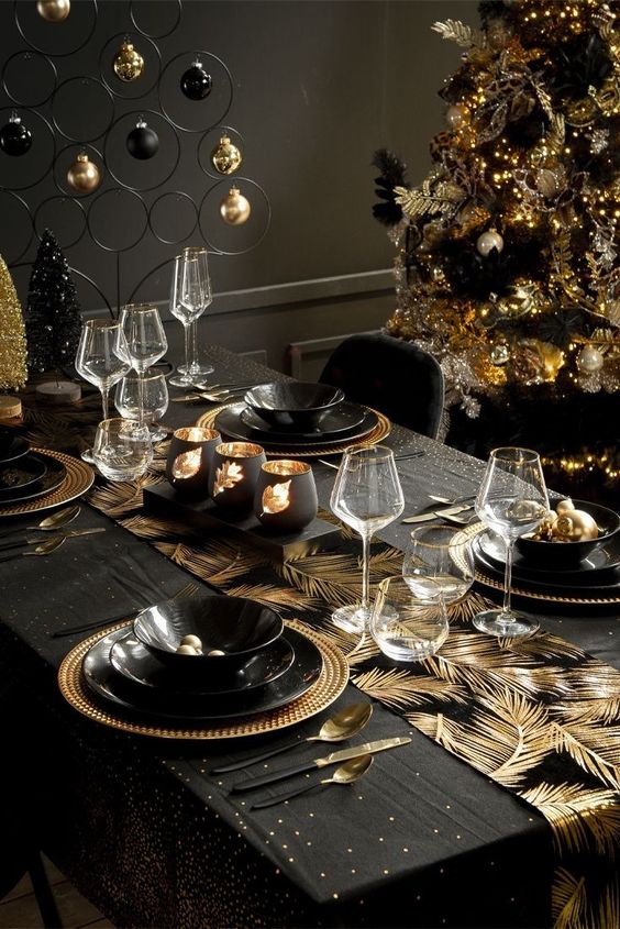 a super glam and shiny Christmas tablescape with a gold feather runner, black and gold porcelain, bottle brush trees