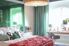 a tasteful maximalist bedroom with a shiny green accent wall, a white forged bed with bright bedding and a rug, a fluffy pendant lamp