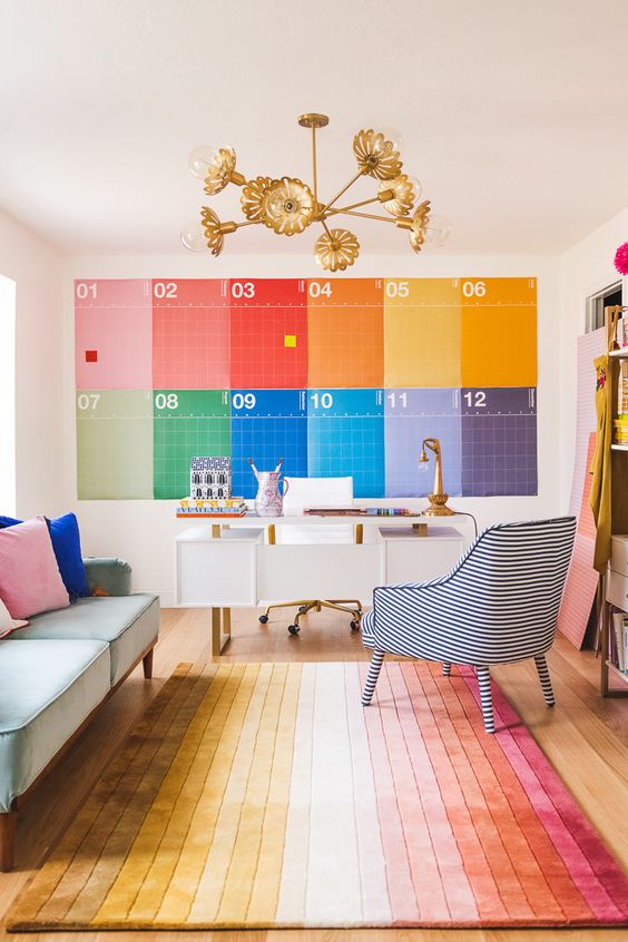 a unique maximalist home office done with all the colors of the rainbow, with a white desk, a pastel sofa and a striped chair just wows