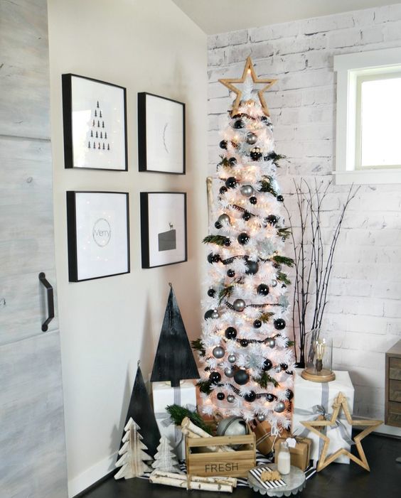 a white Christmas tree decorated with silver and black ornaments and lights, with a wooden star tree topper is cool