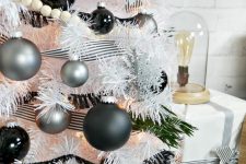 a white Christmas tree decorated with striped ribbons, matte silver and black ornaments and wooden beads is great for a modern space