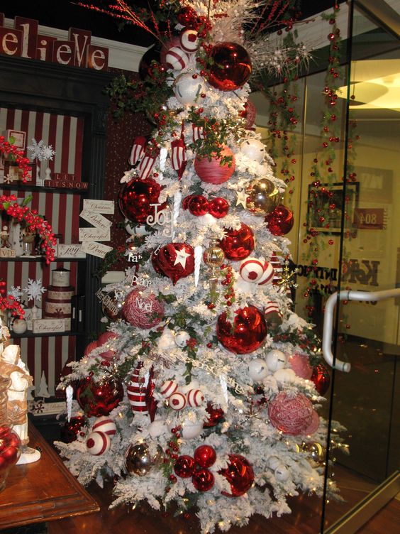 a white Christmas tree with oversized bright pink, white and red ornaments inspired by peppermints is a fun and cool idea