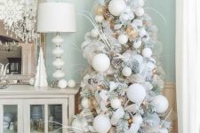 an icy Christmas tree – a flocked one with snowy pinecones, lights, oversized white ornaments and some twigs plus white fabric blooms