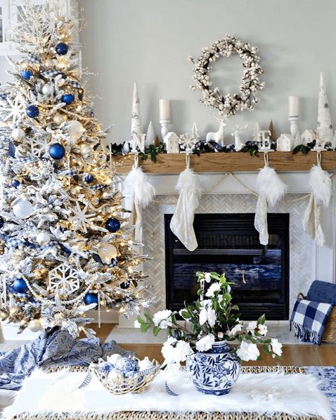 bold coastal Christmas decor with a flocked Christmas tree decorated with navy ornaments, starfish and lights, a white mantel with deer and candles and navy touches in decor