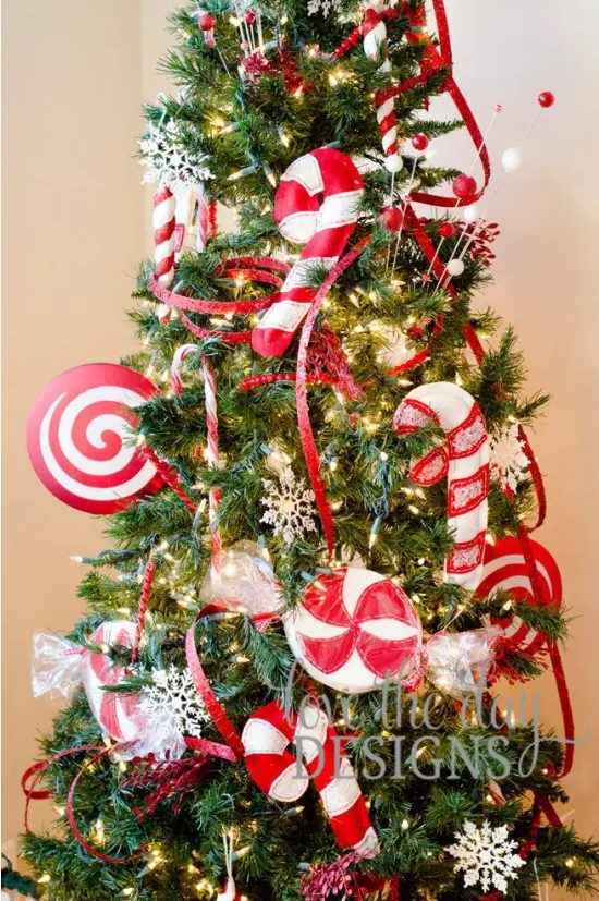 bright Christmas tree decor with red ribbons and oversized red and white fabric peppermints and candy canes looks fun and bold