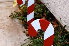 cool outdoor holiday decor – growing greenery accented with candy canes looks very bright and very cool