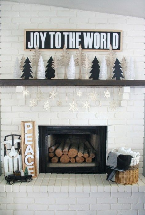 lovely black and white Christmas decor with cardboard Christmas trees and a sign, some firewood, a sleigh, signs and a basket with blankets