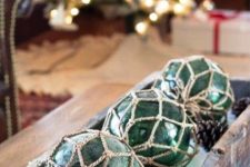 lovely coastal Christmas decor with a shabby chic tray, pinecones, green buoys in net is a cool centerpiece or just decoration to rock