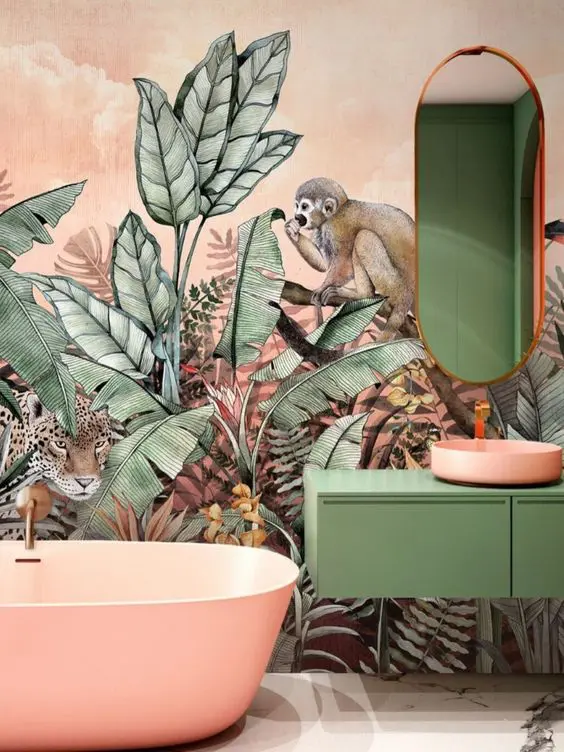tropical maximalist bathroom with jaw dropping wallpaper, a pink bathtub and sink, a green vanity and an oval mirror just wows