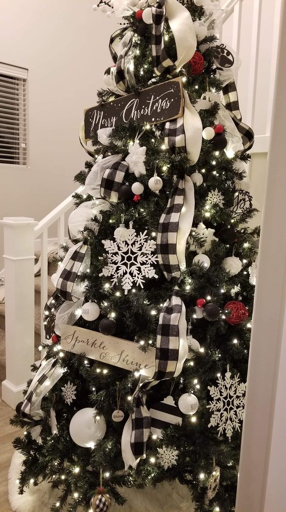 a beautiful Christmas tree decorated with black and white baubles and red yarn ornaments, buffalo check ribbons, snowflakes and stars plus signs