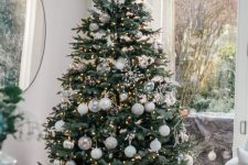 02 a beautiful neutral Christmas tree with white and silver ornaments, lights, pinecones and snowflakes is a very chic and delicate idea