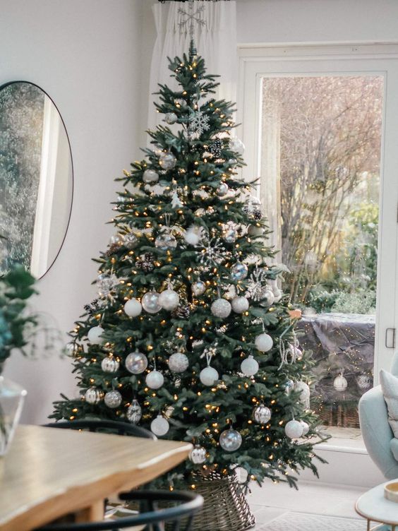 a beautiful neutral Christmas tree with white and silver ornaments, lights, pinecones and snowflakes is a very chic and delicate idea