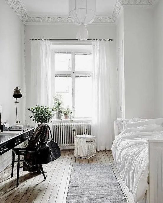 a serene and airy guest bedroom with lots of white and a vintage black desk plus chair to stand out