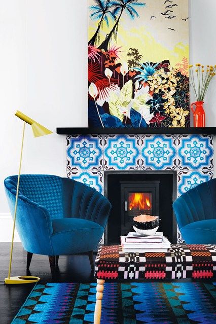 electric blue chairs, a bright blue printed rug, a bold blue tile fireplace and a colorful artwork create color galore