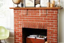 03 a beautiful non-working red brick fireplace with a chest with books, a stained mantel with candles and artworks and a globe