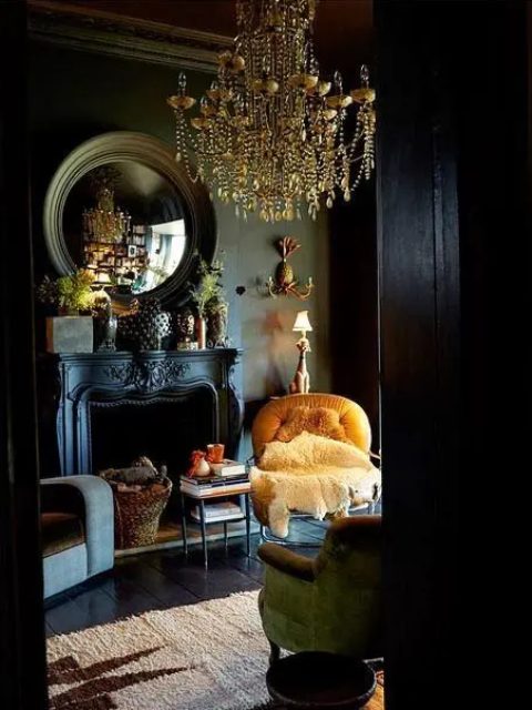 a black painted vintage fireplace with firewood in a basket adds an exquisite feel to this gorgeous moody living room with a statement chandelier
