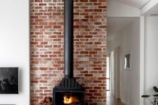 05 a black metal hearth surrounded with red brick and placed on a floating shelf for storing firewood here