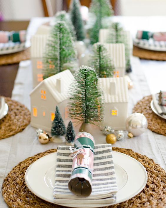 a festive centerpiece of green bottle brush Christmas trees, mini lit up houses, metallic ornaments is beautiful and cozy