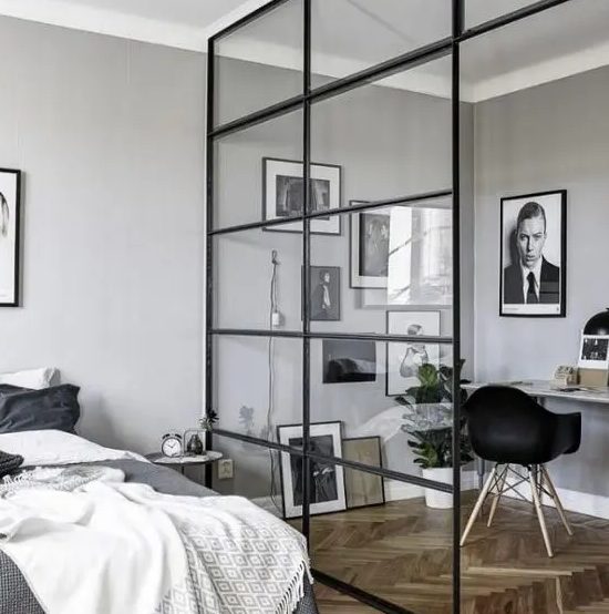 a masculine bedroom and a workspace separated with a glazed framed wall is a cool way to organize a space