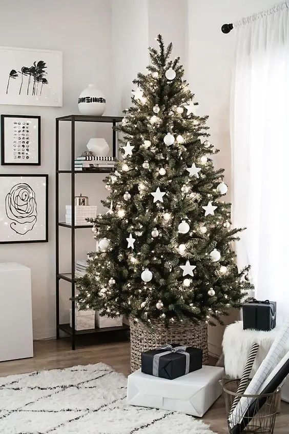 a classic Christmas tree decorated with only white and silver ornaments and lights and placed into a basket is a fresh and modern Scandi inspired idea to try