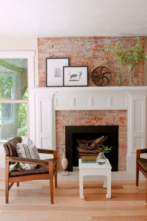 a cozy mid-century modern living room with a red brick fireplace, a chic white mantel with decor that matches a stool