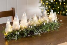 07 a lit up bottle brush Christmas tree centerpiece with ferns and silver ornaments is a fun and chic idea