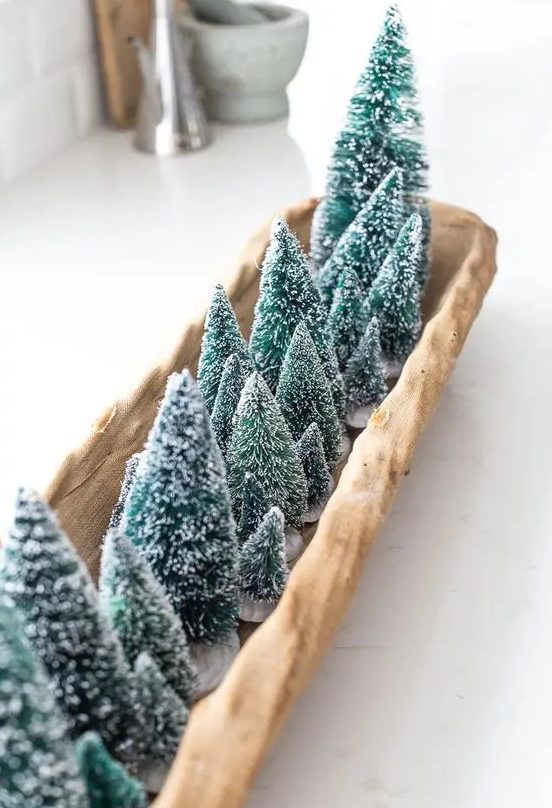 a long wooden tray with lots of green bottle brush trees is a pretty and lovely centerpiece for Christmas