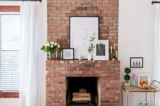 09 a lovely red brick fireplace with a matching mantel, artworks, candles and blooms and greenery is a chic addition to the space