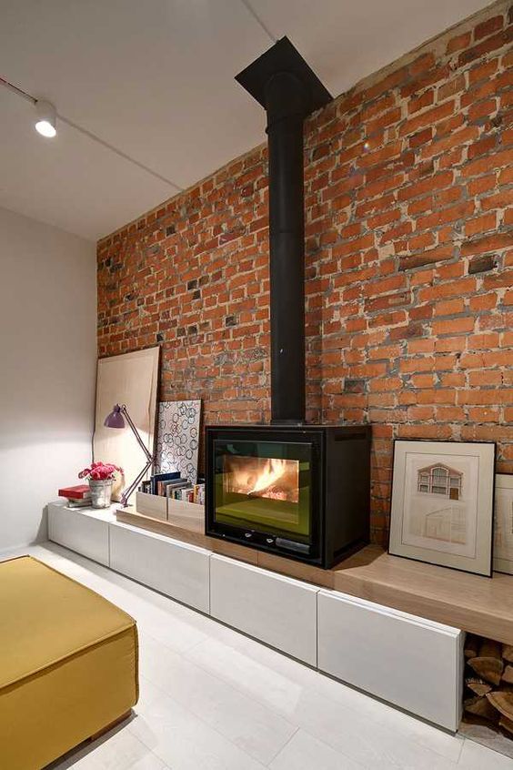 a minimalist space with a red brick wall that accents the black metal heart and artworks that surround it for more chic