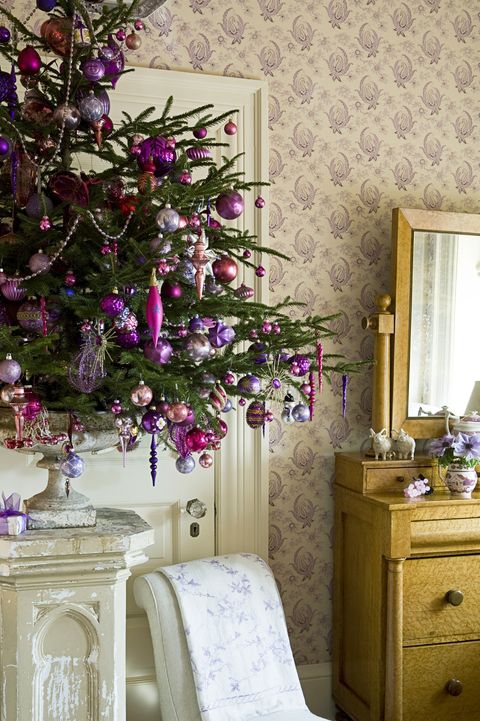 a small Christmas tree in a vintage urn, with fuchsia, purple and silver Christmas ornaments and beads, lights and icicles