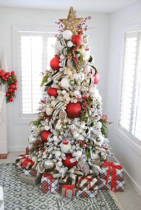 an extra bold Christmas tree decorated with oversized white, red and green ornaments, berries, ribbons and a marquee star topper