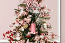 11 a bright Christmas tree decorated with pink and rose gold ornaments, cupcakes and snowmen, candles and candy canes plus candy canes as a tree topper