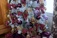 11 a sophisticated flocked Christmas tree with purple, clear and purple print ornaments, purple and gold ribbon bows