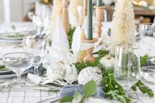 12 a neutral Christmas tablescape with a plaid tablecloth and blue napkins, neutral bottle brush trees, green candles and simple porcelain