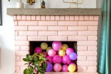 12 a painted blush brick fireplace filled with colorful balloons and with potted plants all around