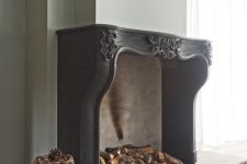12 an oversized fireplace with a gorgeous ornated vintage black mantel, with firewood and pinecones inside is fantastic