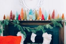 14 a bold modern Christmas mantel styled with various bottle brush trees and an evergreen garland with white stockings