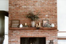 14 a red brick fireplace with a rich-stained mantel, a modern and chic firewood stand, lovely decor on the mantel is cool