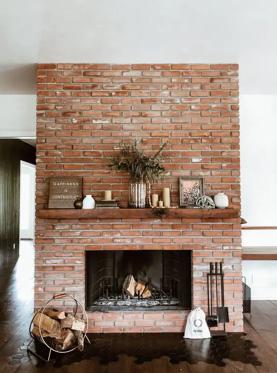 a red brick fireplace with a rich stained mantel, a modern and chic firewood stand, lovely decor on the mantel is cool