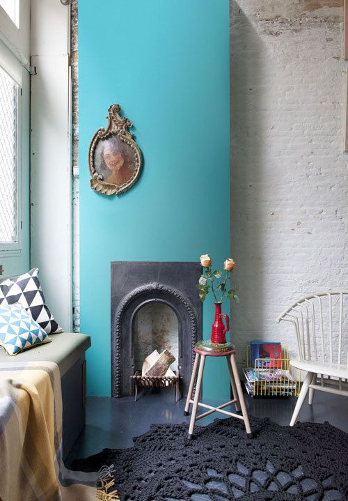 a chic nook with a shabby chic brick wall, a vintage fireplace with a bold blue surround, a doily rug and an upholstered bench