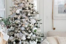 15 a flocked Christmas tree with white, silver and emerald ornaments, feathers, pinecones and grey ribbons is a lovely idea