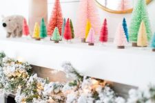 15 a fun modern Christmas mantel with colorful bottle brush trees, a flocked evergreen garland with lights