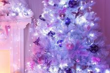 15 a white Christmas tree with pink and purple ornaments, lights and a tree topper plus candles around is amazing