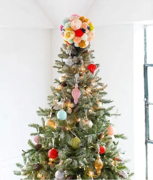 a colorful pompom Christmas tree topper matches the colorful decor fo the tree and adds fun to the decor