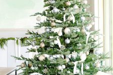 17 a luxurious neutral Christmas tree with silver, gold, white and light green ornaments, white ribbon bows, lights, snowflakes is wow